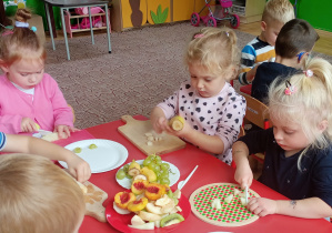 Dzieci wykonują sałatkę owocową